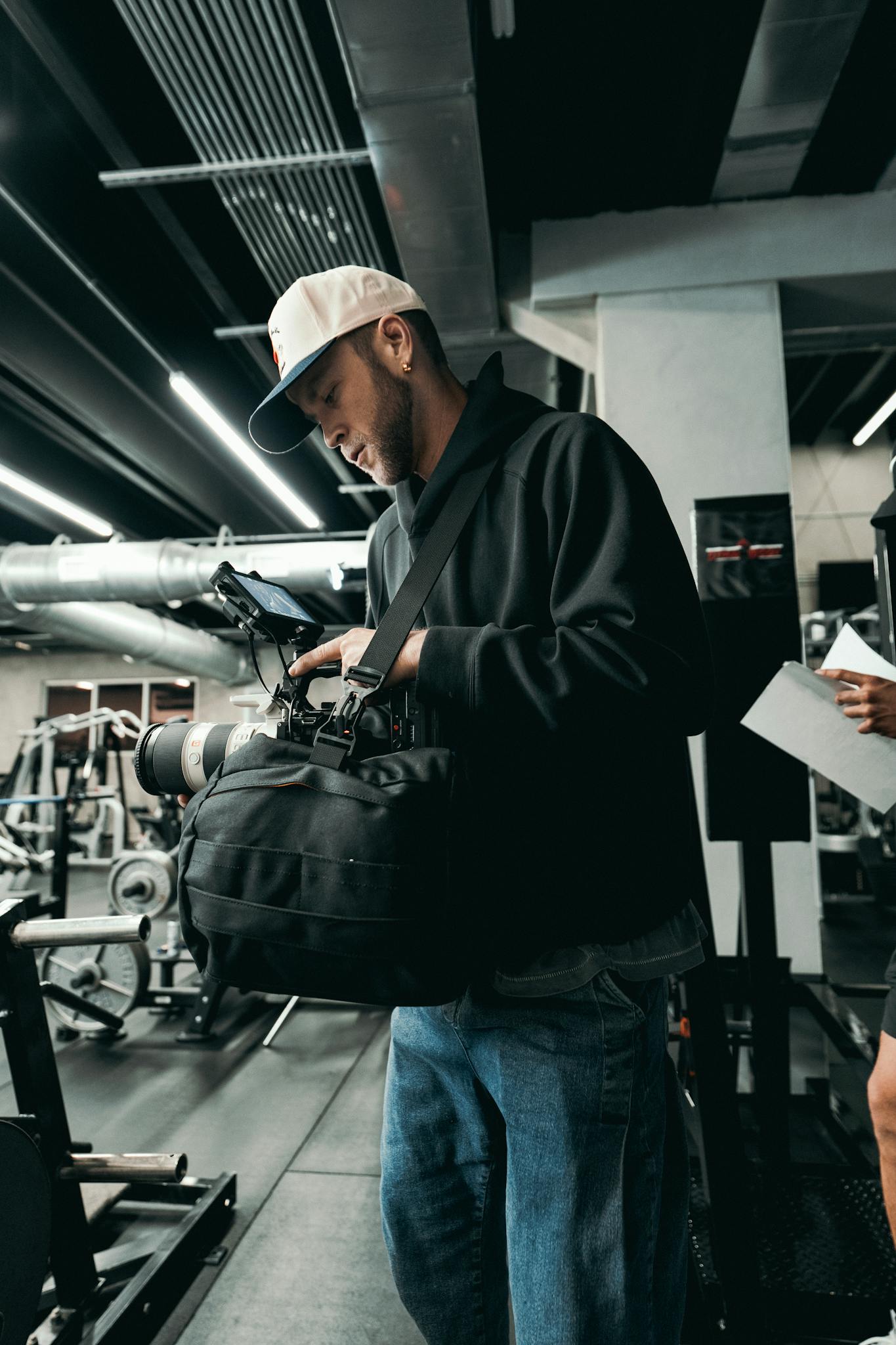 Filmmaker setting up camera gear in a modern gym for video production.